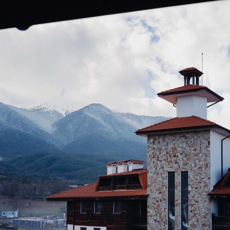 a lighthouse on a building with mountains in the background at Pirin Peaks Residence - next to Ski Lift in Bansko