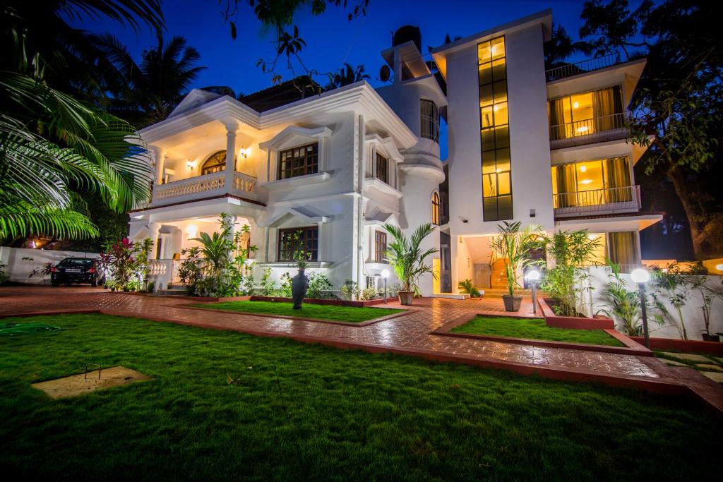 a large white house with a lawn in front of it at Pinnacle Holiday Homes in Arpora