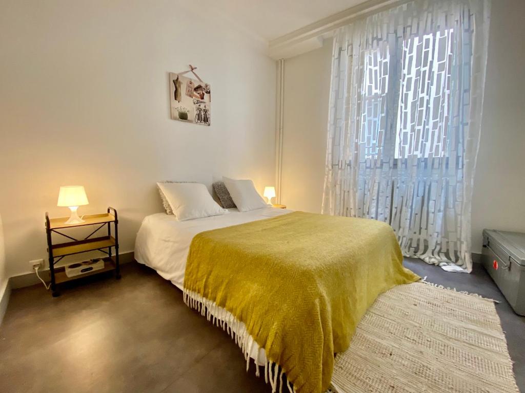 une chambre avec un lit et une grande fenêtre dans l'établissement Charmant 2 pièces au coeur de Paris, à Paris