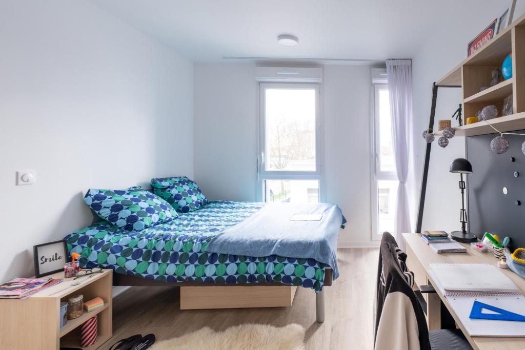 une petite chambre avec un lit et un bureau dans l'établissement Appartement cosy, à Bagneux