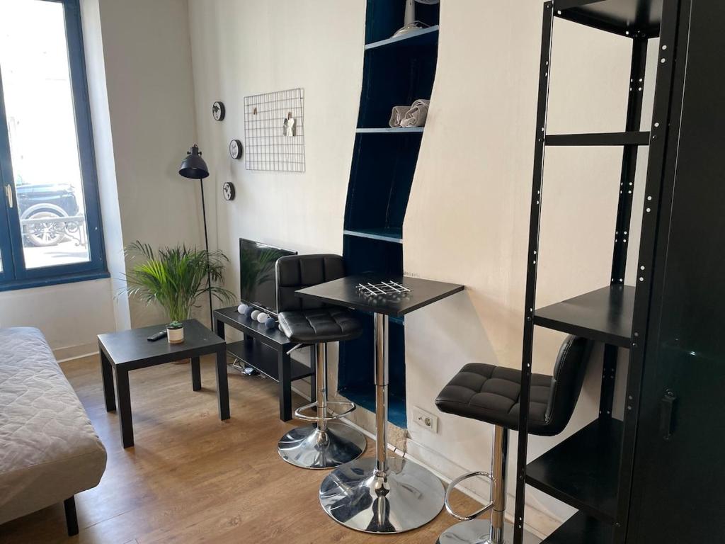 - un salon avec des étagères noires et une table dans l'établissement Charmant studio départ tardif, à Orléans