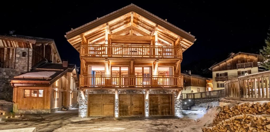 une maison en bois avec une terrasse au-dessus dans l'établissement Chalet KALINKA, MERIBEL,15 PERSONNES, PISCINE, SPA, MASSAGE, CINEMA ET PLAYROOM, à Les Allues