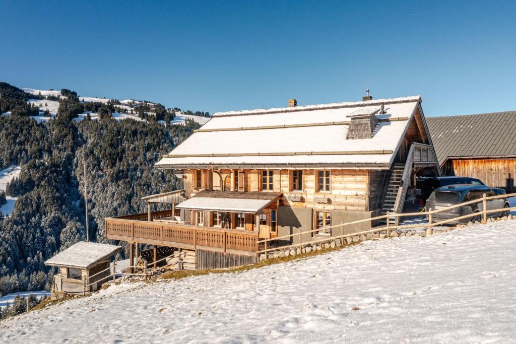una gran casa de madera en la cima de una colina nevada en Panoramic 5 Bedroom Luxury Chalet with Butler, en Château-d'Oex