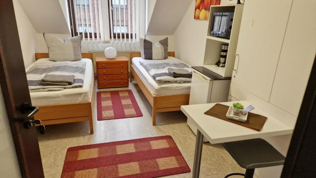 a small room with two beds and a table at Zimmer C in Mönchengladbach
