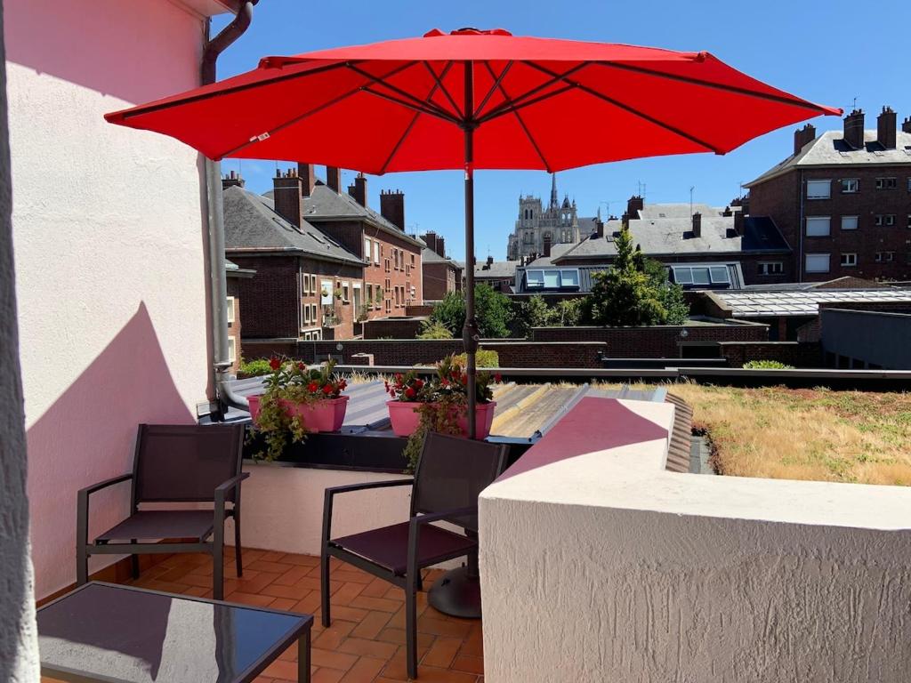 une terrasse avec un parasol rouge et deux chaises dans l'établissement Terrasse vue cathédrale et beffroi hyper centre, à Amiens