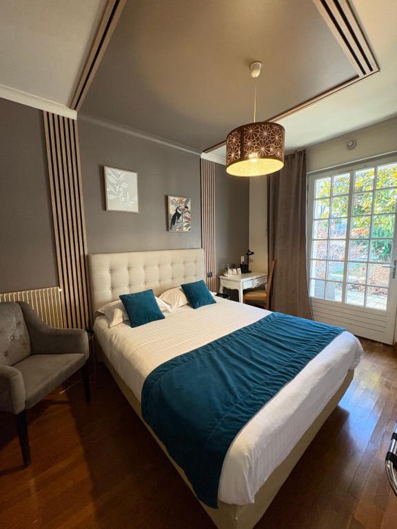 a bedroom with a large bed and a chair at Hôtel La Vinaigrerie LOGIS in Joinville