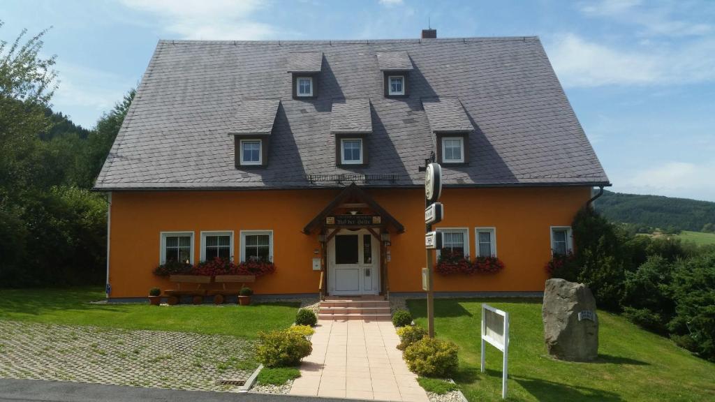 a orange house with a gray roof at Auf der Heide Gasthof & Pension in Waltersdorf