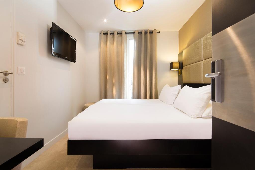 sypialnia z dużym białym łóżkiem i telewizorem w obiekcie Le Relais du Marais w Paryżu