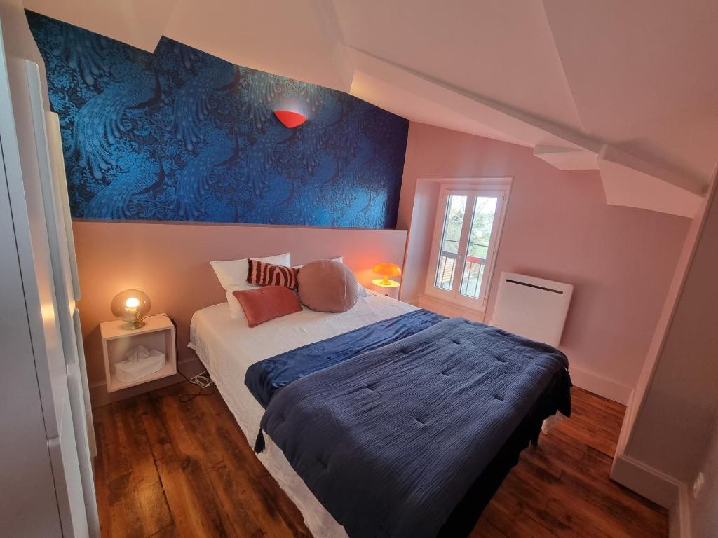 une chambre avec un lit et un mur bleu dans l'établissement Villa St-Gau, à Saint-Gaudens