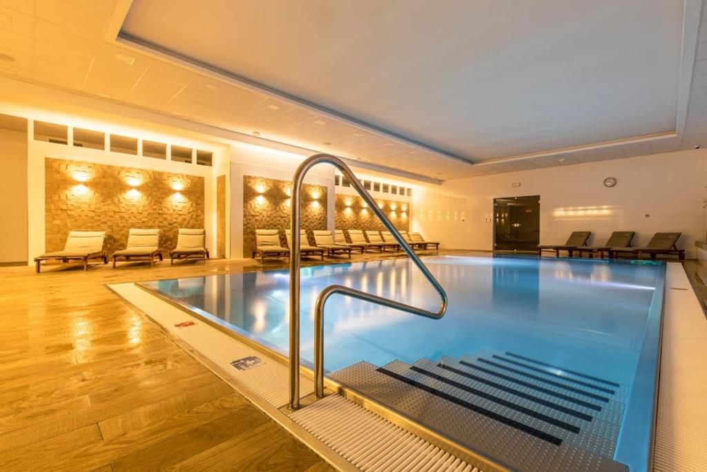 a large swimming pool in a large room with tables and chairs at Wellness Moser Apartments in Karlovy Vary