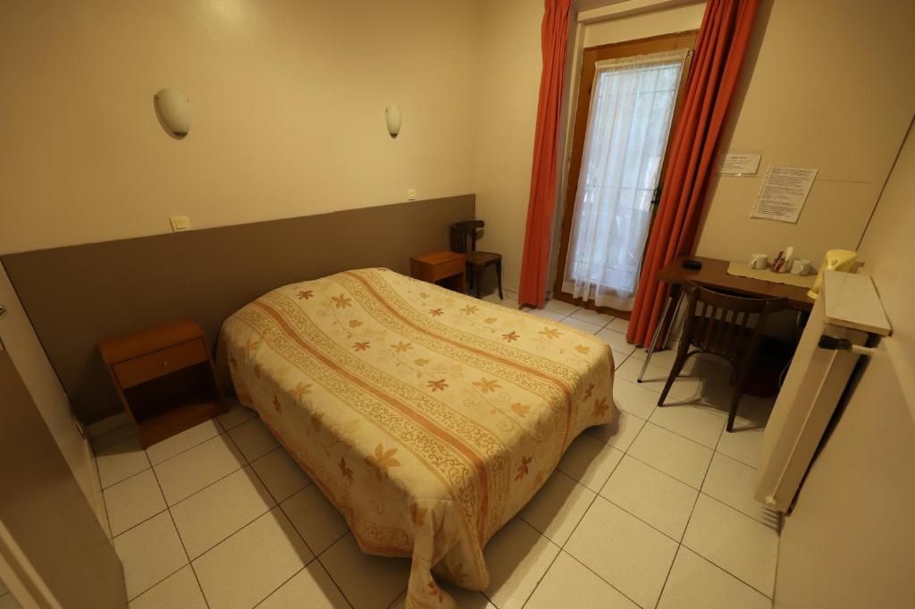 a bedroom with a bed and a table and a window at Hôtel du Roussillon in Paris