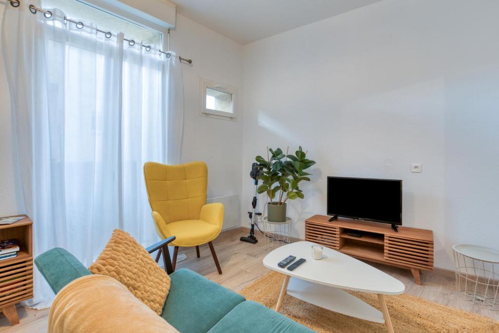 een woonkamer met een bank en een tv bij Le Voltaire pour 4 in Sète
