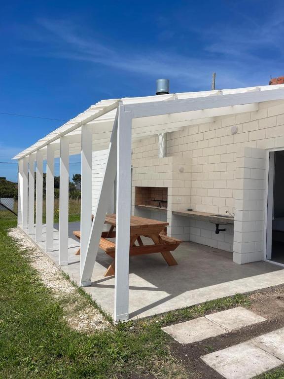 a picnic shelter with a picnic table and a bench at Ola Santa in Colonia Chapadmalal