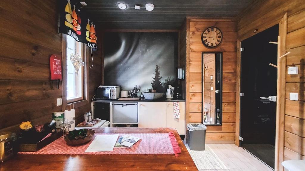 a room with a table and a clock on the wall at Cozy guesthouse with sauna, private entrance in Sodankylä