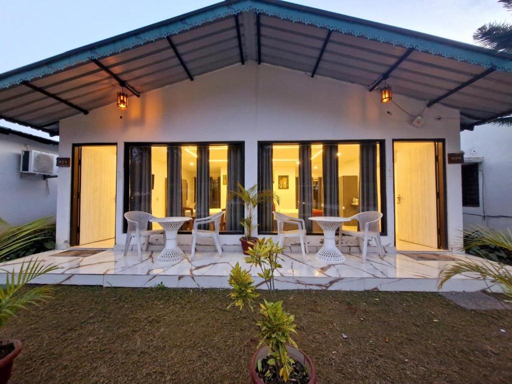 une maison avec des portes en verre et des chaises blanches sur une terrasse dans l'établissement Six seasons resort Jim Corbet, à Kālādhūngi