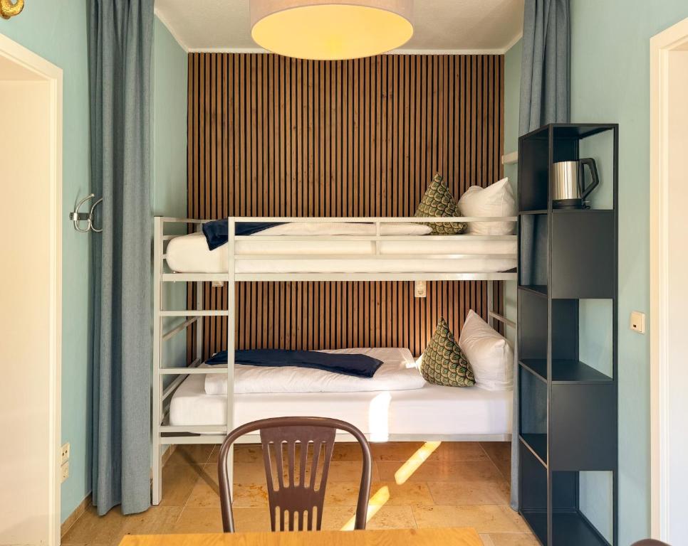a bedroom with bunk beds with a table and a chair at Villa Fantasia Budget Boutique Hotel in Füssen