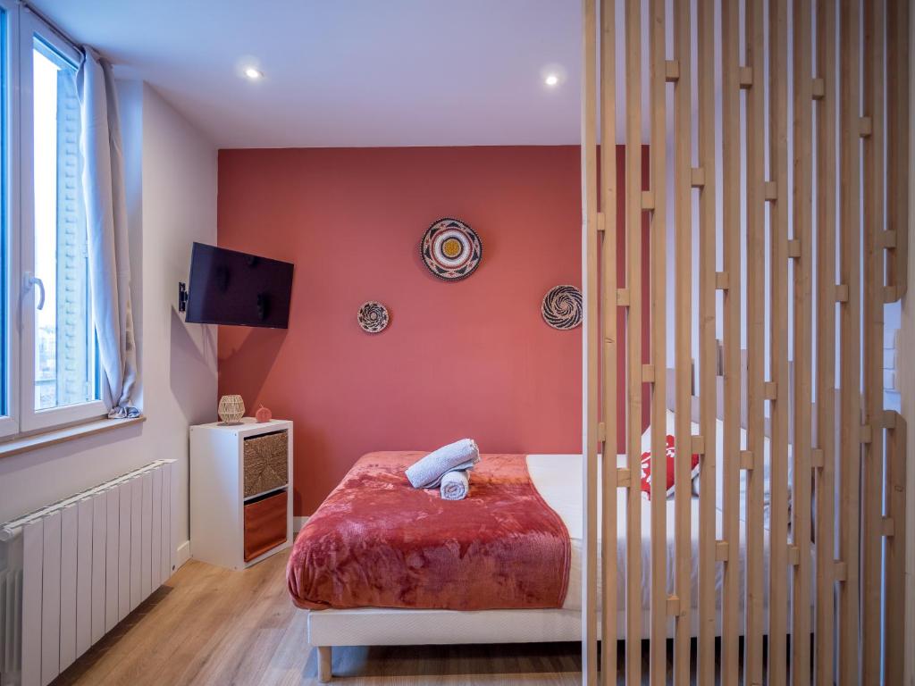 ein Schlafzimmer mit einem Bett und einer roten Wand in der Unterkunft Le Cosy Express in Villefranche-sur-Saône