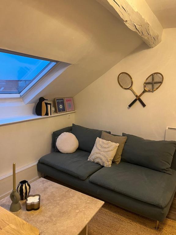 - un salon avec un canapé et des raquettes de tennis sur le mur dans l'établissement La Cachette, à Angers