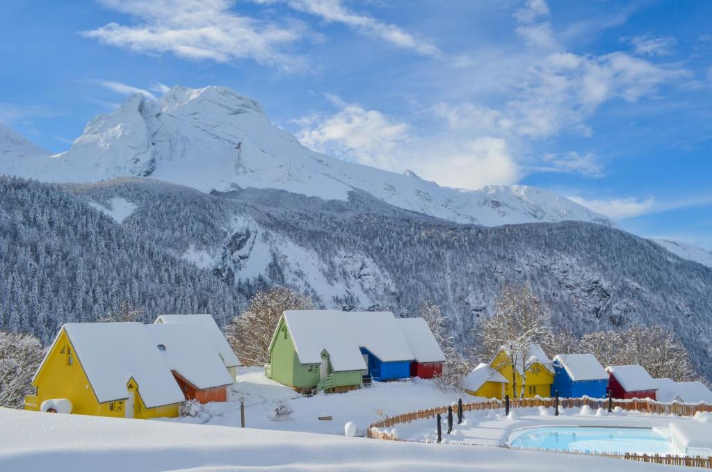 een groep hutten in de sneeuw met een berg bij ISKÖ CHALETS-HÖTEL, Col d'Aubisque in Gourette