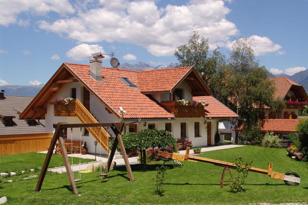 una casa con un parque infantil delante de ella en Oberlindnerhof en San Lorenzo di Sebato