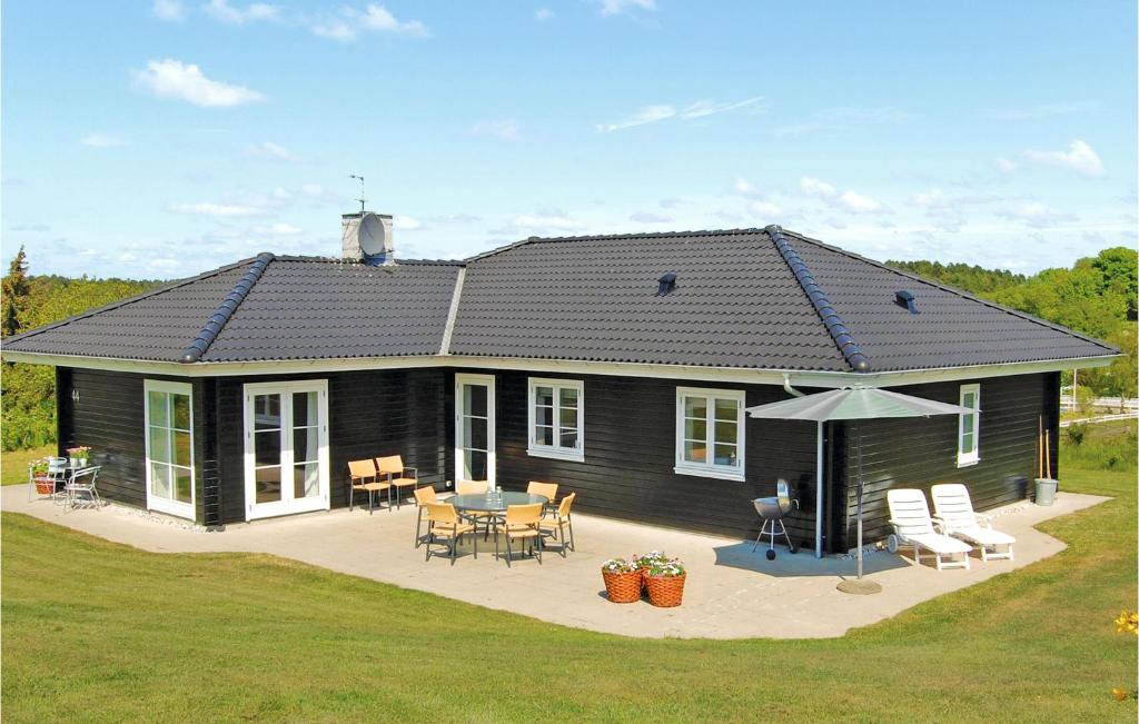 a black house with a patio and a table and chairs at Holiday Home Ravnsvej Ebeltoft Denm in Ebeltoft