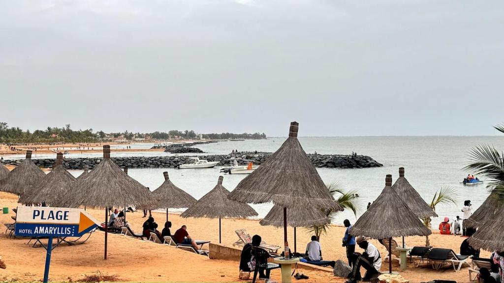 Un grupo de personas sentadas en una playa con sombrillas en charmante villa en résidence en bord de mer, en Saly Portudal