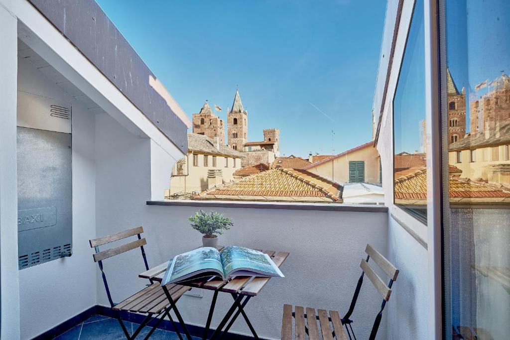 a balcony with two chairs and a table with a book at Italianway - Tra le Torri in Albenga