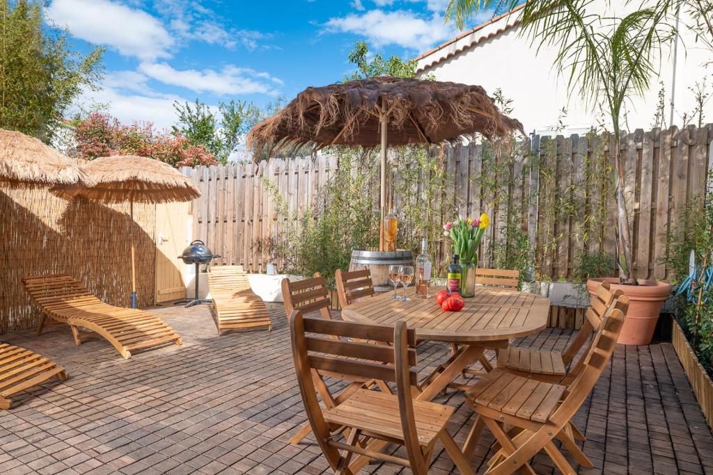 ジュアン・レ・パンにあるAppartement 6 pers Jardin Privé La Cabane Bambou - Mandara Beach , Antibes French Rivieraのパティオ(木製のテーブル、椅子、パラソル付)