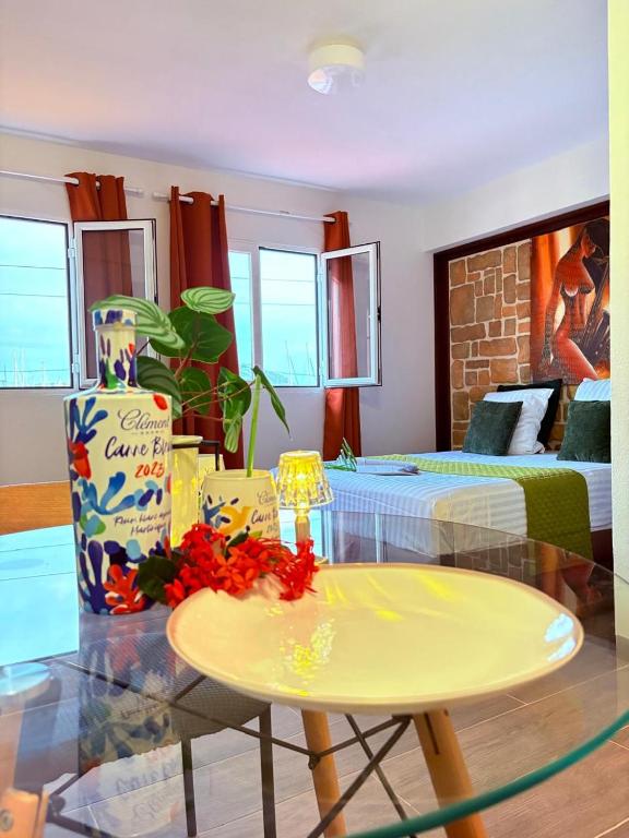 a living room with a glass table and a bedroom at Le Ti Marinois 5 in Le Marin