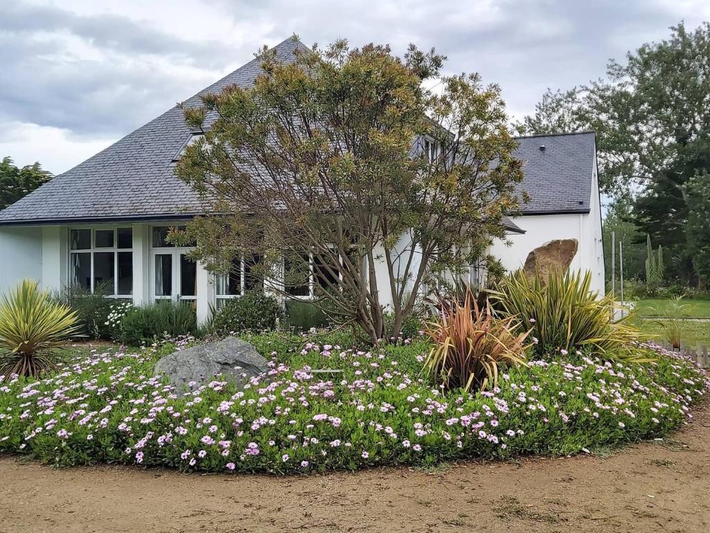 une maison avec un jardin de fleurs devant elle dans l'établissement Natural green group villa classified 4 ears, à Penmarcʼh