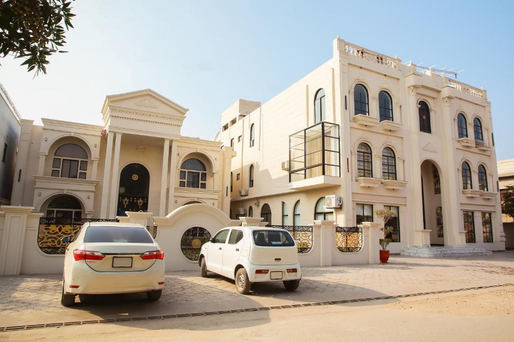 two white cars parked in front of a building at Grand Shalimar Hotel in Multan