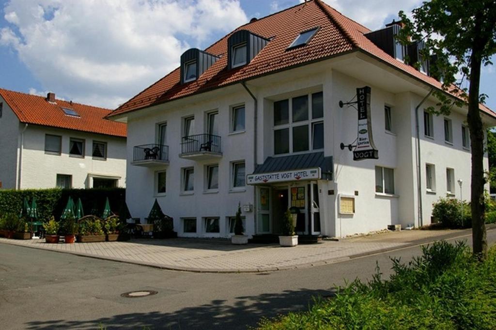 a white building with a red roof on a street at Hotel Vogt in Bad Driburg