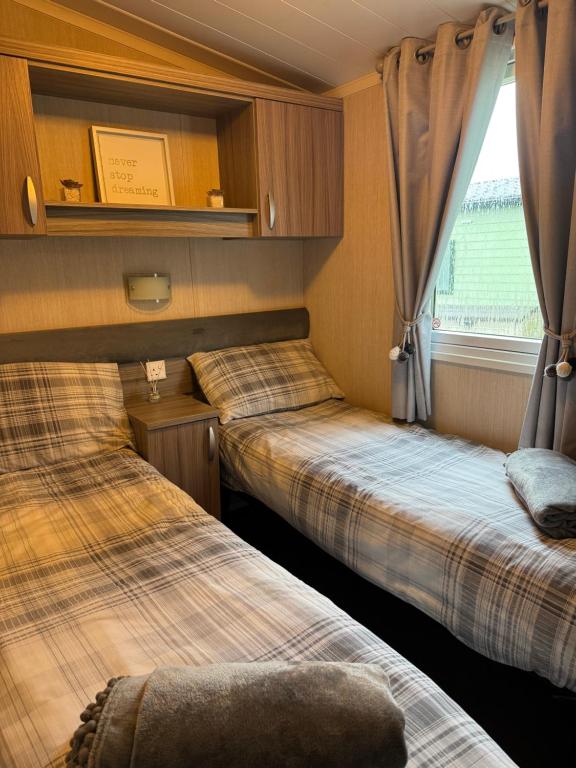 two beds in a small room with a window at Silver Birch Retreat - Percy Woods Country Retreat With 18 HOLE FREE GOLF in Alnwick