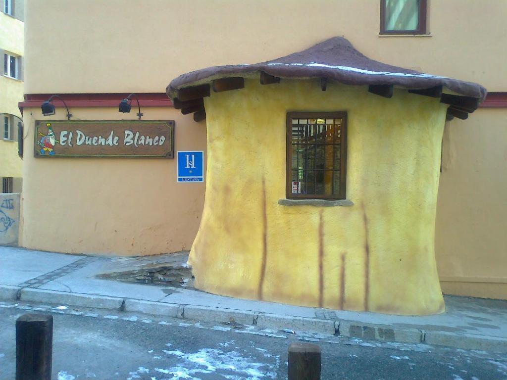 un piccolo edificio con un cartello sul lato di un edificio di Hostal El Duende Blanco a Sierra Nevada