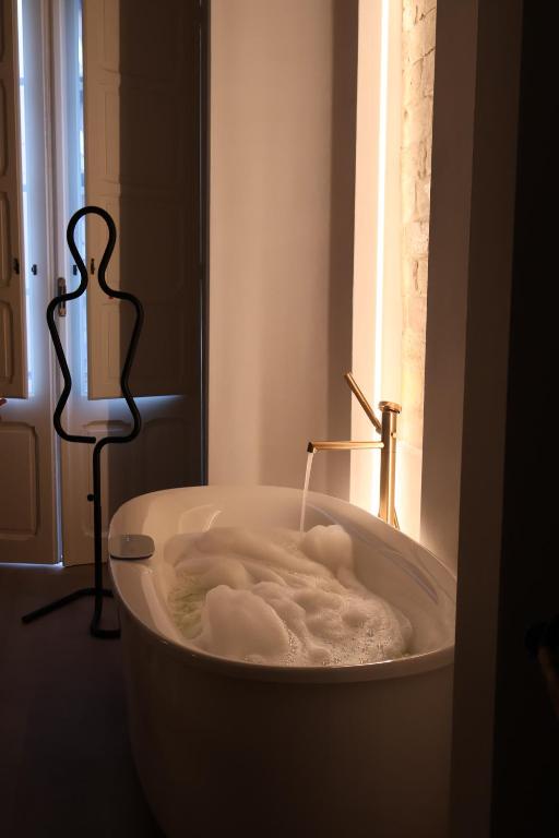 a white bath tub in a room with a window at Pedra Bianca Luxury Rooms in Cagliari