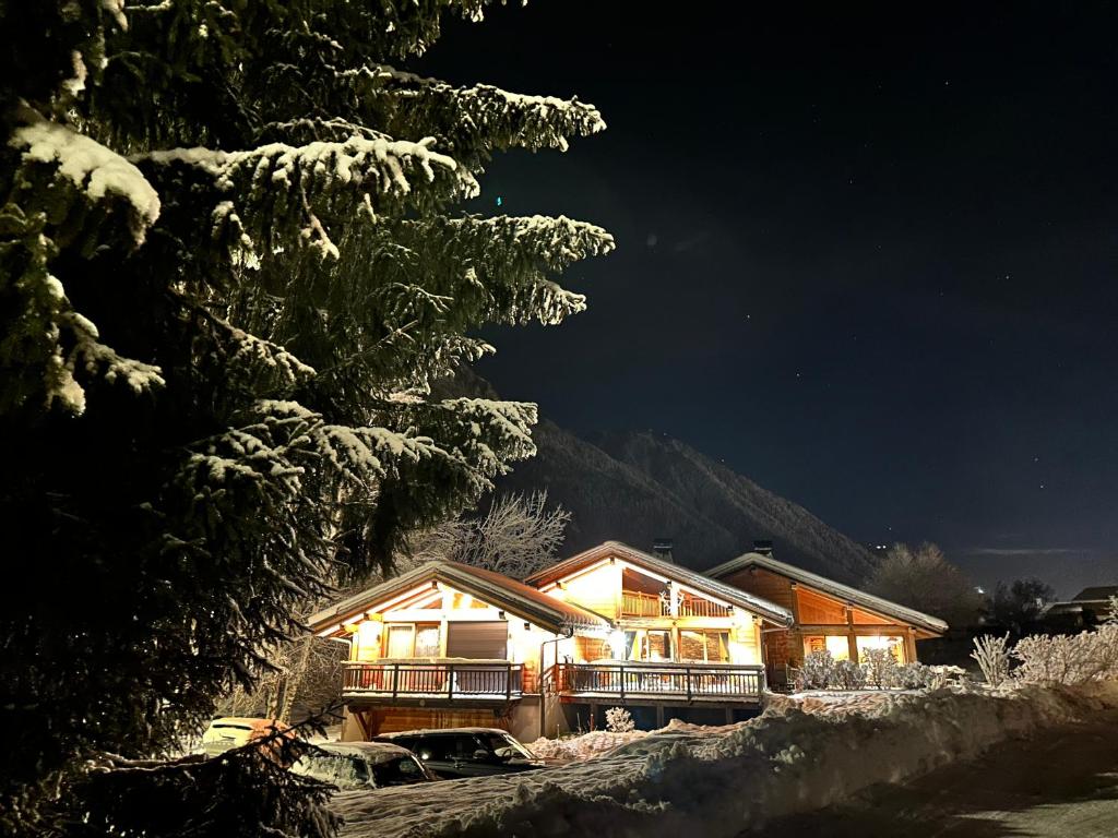 une maison éclairée la nuit dans la neige dans l'établissement Grand chalet Le Trappeur - Chamonix, à Chamonix-Mont-Blanc