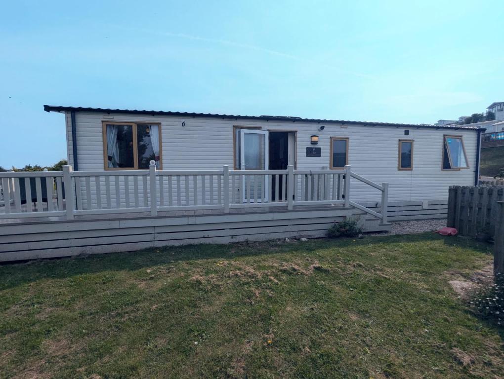 a white house with a porch and a fence at BRIGHT and COMFORTABLE HOLIDAY HOME SWANAGE BAYVIEW HOLIDAY PARK in Swanage