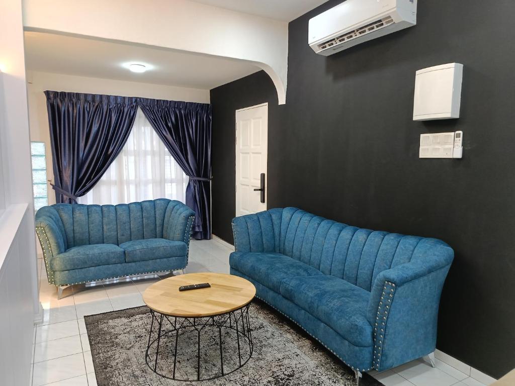 a living room with two blue couches and a table at Newstar Jacuzzi Homestay Near Jonker Kota Laksamana Melaka in Melaka