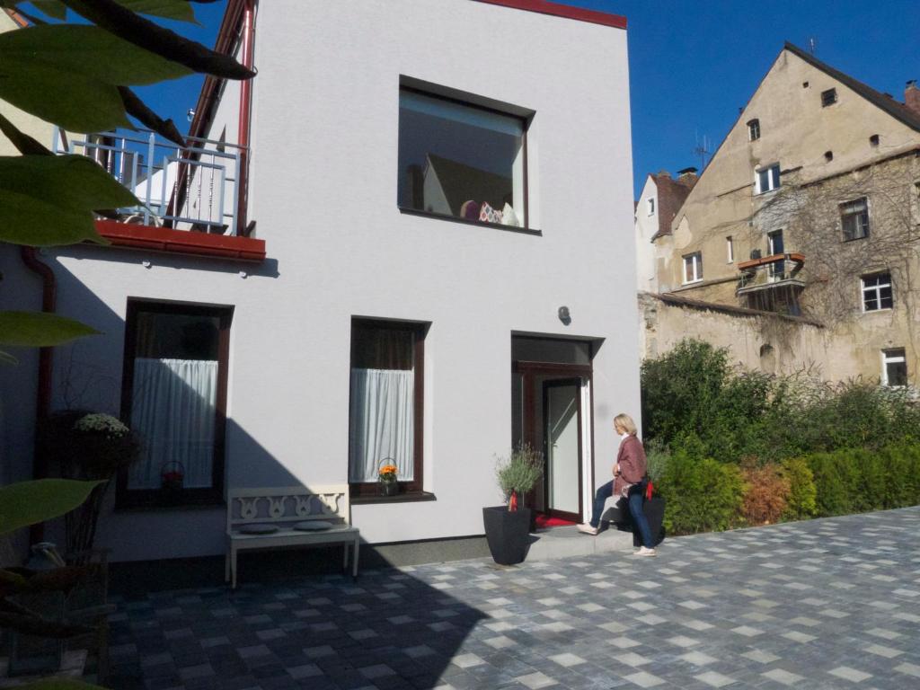 a man sitting on the porch of a white building at Boutique Hotel Frieden in Weiden