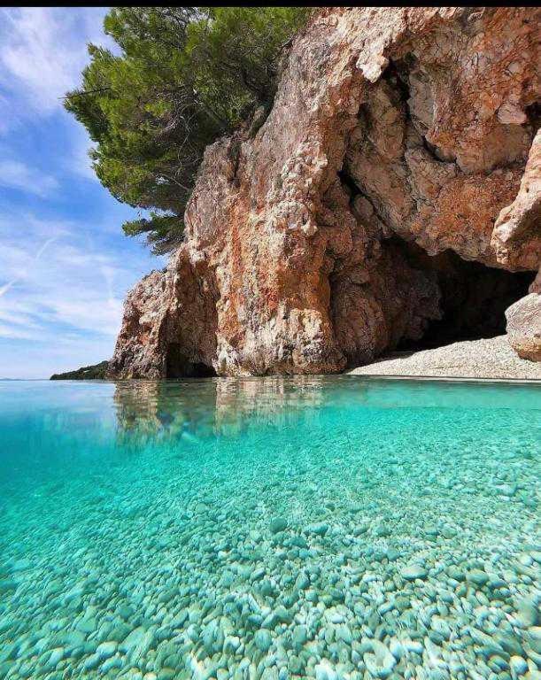 a large body of water next to a rocky cliff at Studioapartman Pink Živogošće in Živogošće