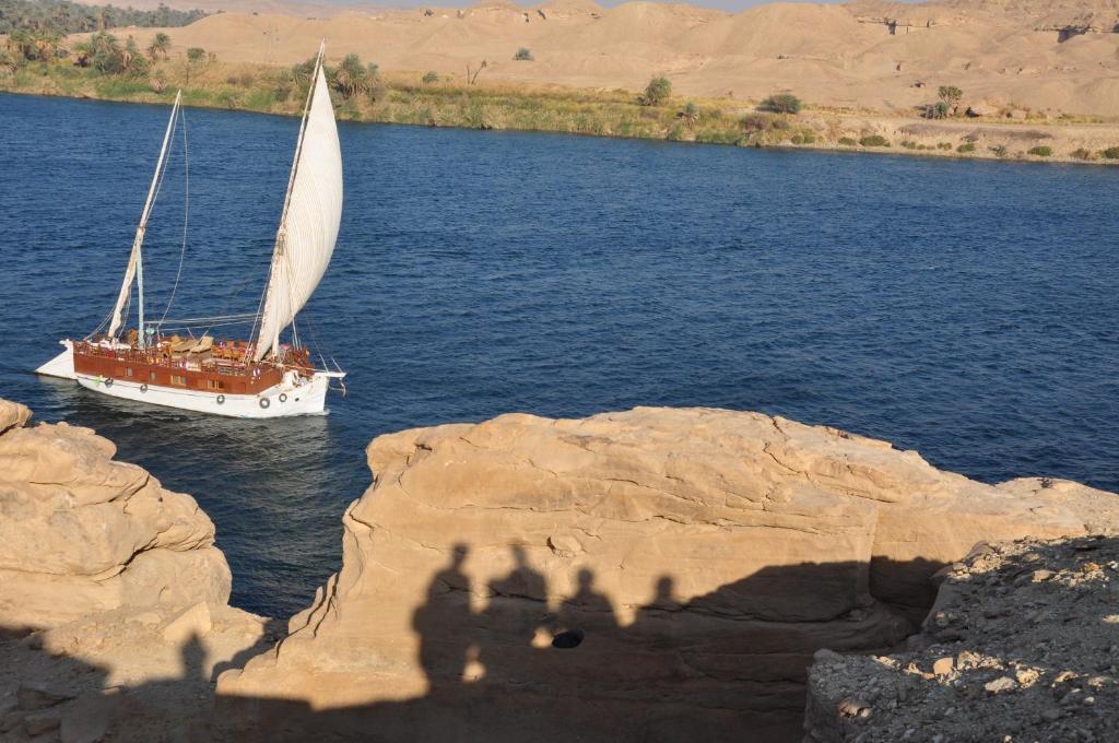 a boat on the water with a shadow of a photographer at Amélia Sandal in Esna