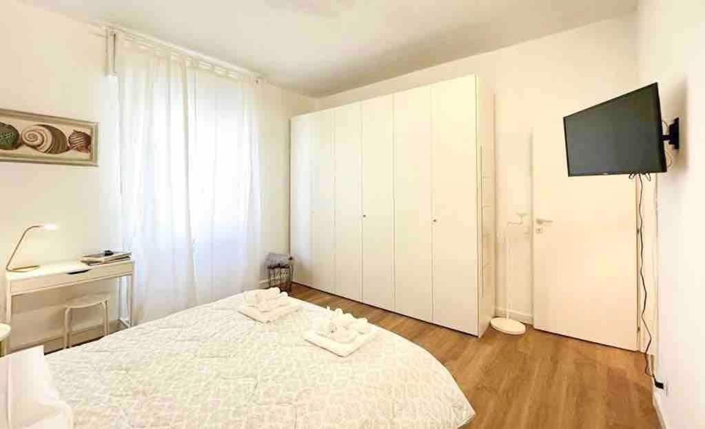een witte slaapkamer met een bed en een flatscreen-tv bij La Casetta in Le Grazie