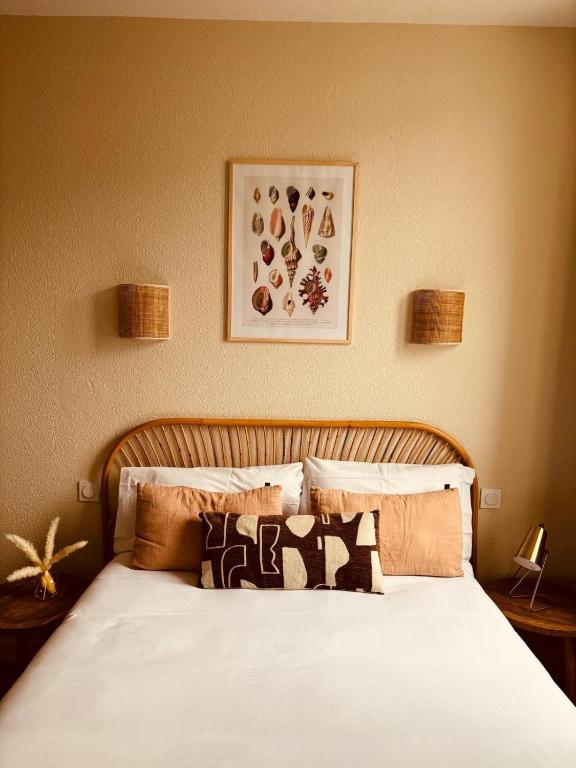 un lit avec des draps blancs et des oreillers dans une chambre dans l'établissement Hôtel Le Britannic - centre gare-, à Saint-Malo