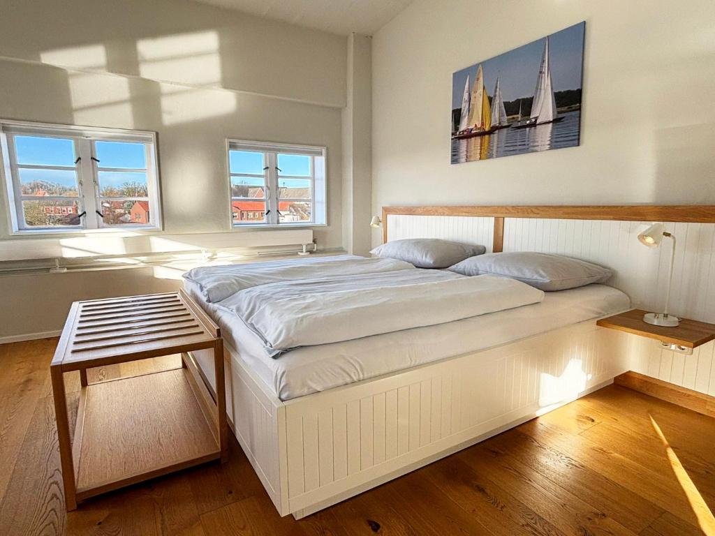 een wit bed in een kamer met 2 ramen bij Pier 18 im Pierspeicher in Kappeln