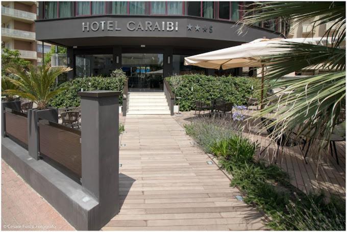 a walkway in front of a hotel with an umbrella at Hotel Caraibi - Breakfast Until 11-00 and Dinner-Mirabilandia Partner in Milano Marittima