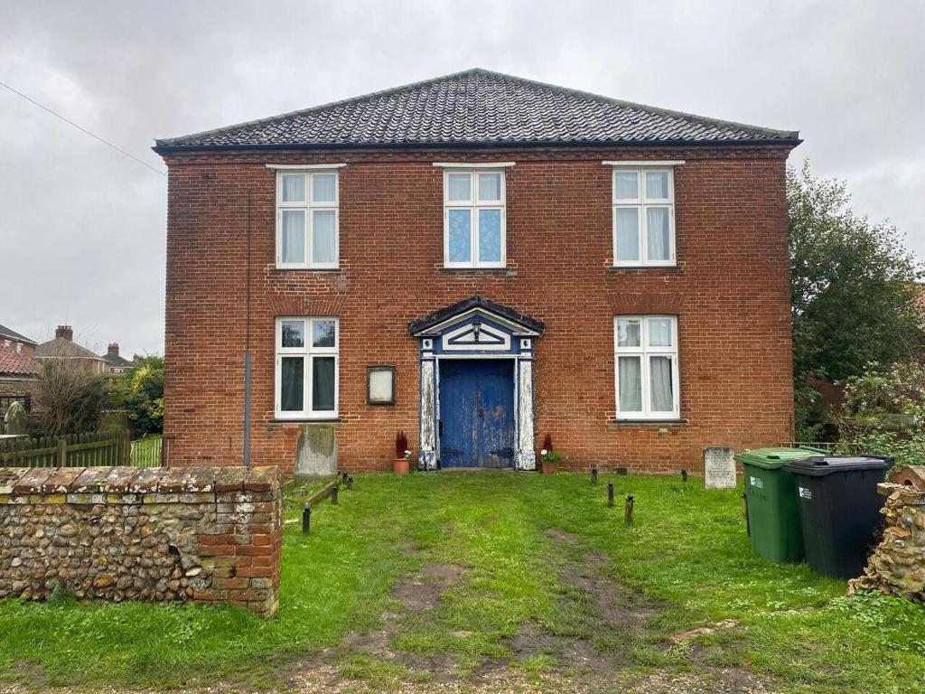 a brick house with a blue door in the yard at Norfolk Chapel hideaway in Briston
