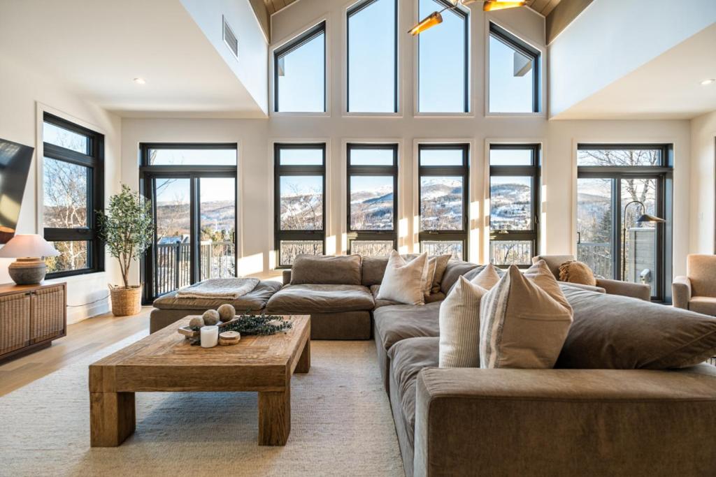 a living room with a large couch and windows at Verbier 6-203 Family Luxury Retreat in Mont-Tremblant
