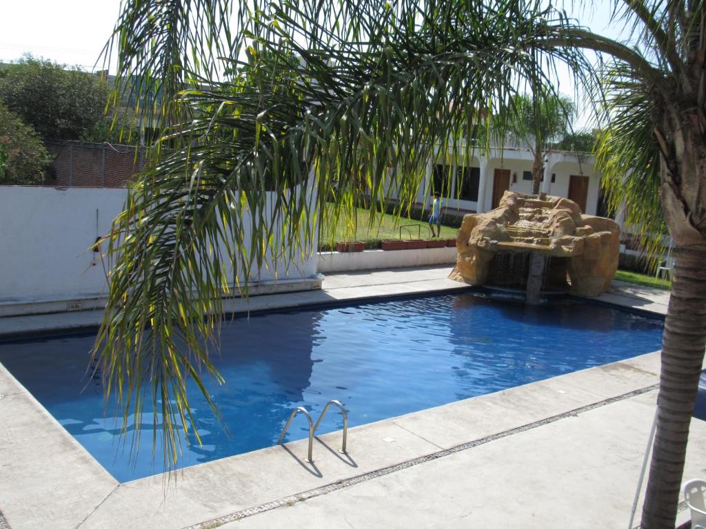 a pool with a palm tree and a fountain at Hotel Real de Cuautla in Cuautla Morelos