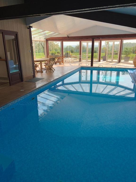 une grande piscine avec de l'eau bleue dans un immeuble dans l'établissement Charmante maison avec piscine, à Saint-Marc-sur-Couesnon