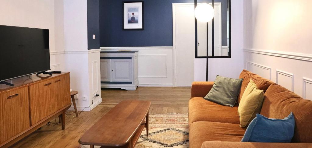 a living room with a couch and a tv at Le Square in Le Havre